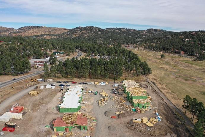 Aerial view of Elk Meadows construction site in Ruidoso, NM showing building framing with green sheathing