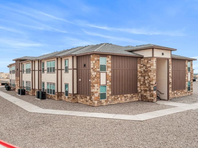 Exterior of Wells of Artesia apartment building in Artesia, NM with brown brick and stone facade